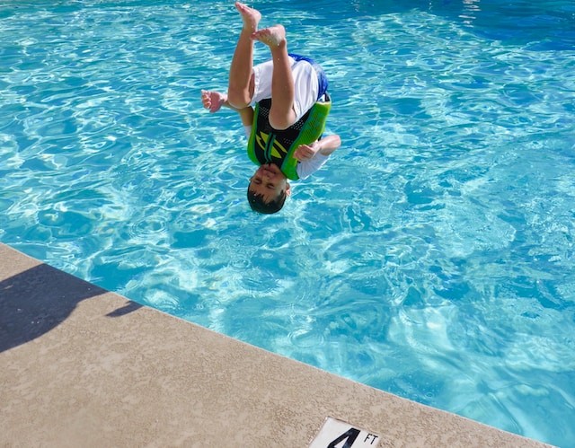 young boy jumping in pool